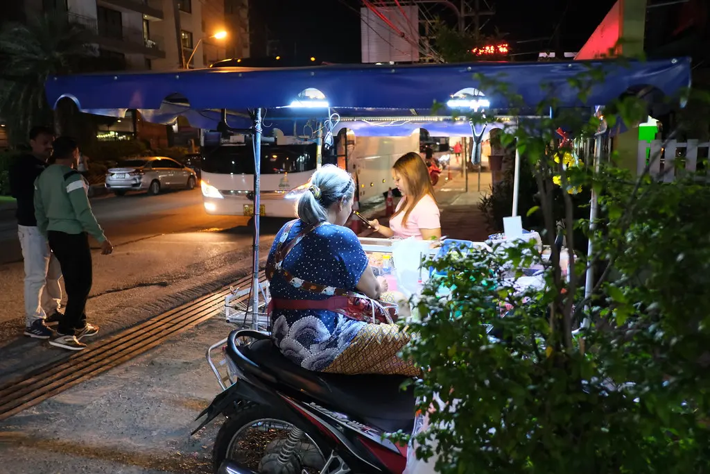 DSCF0789: a woman sitting on a scooter in front of a food cart